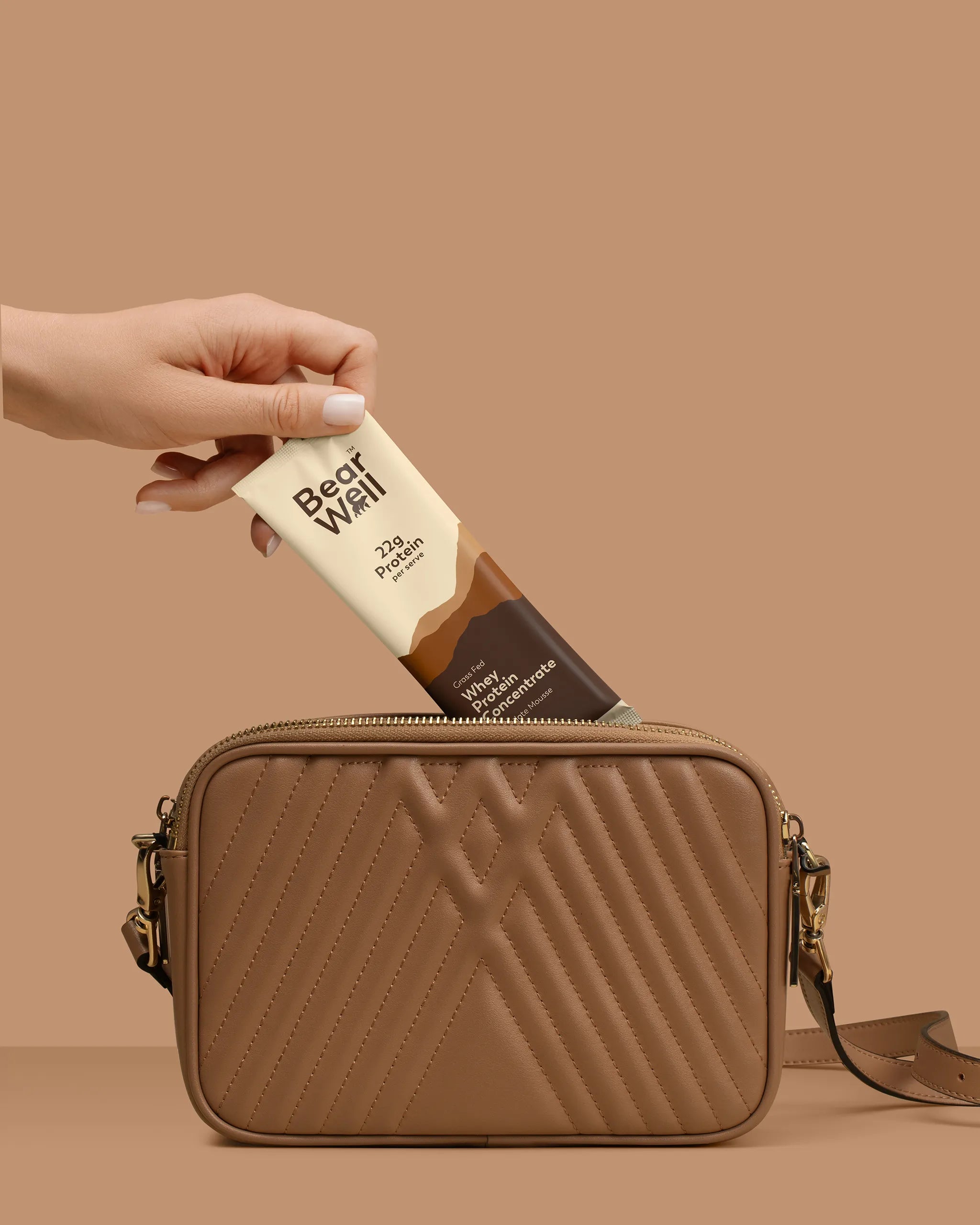 BearWell Whey Chocolate Mousse Sachet being placed into a brown handbag, showcasing the complete product and product attributes